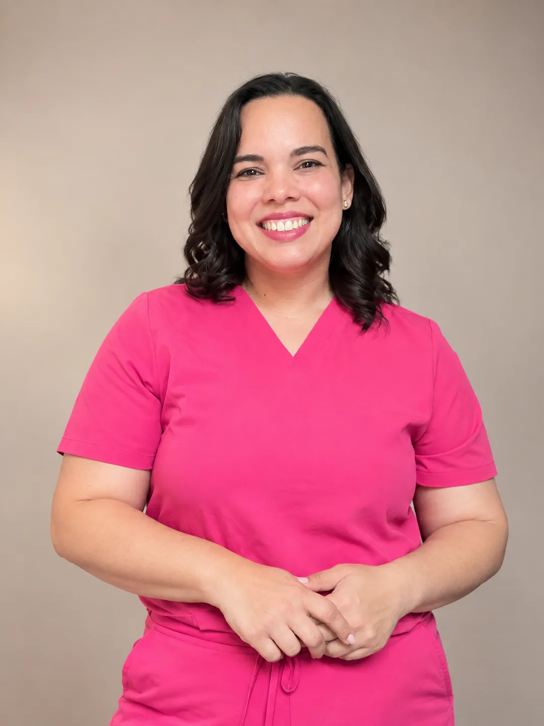 La Dra. Laura Olivares, de pie, en uniforme médico rosado.